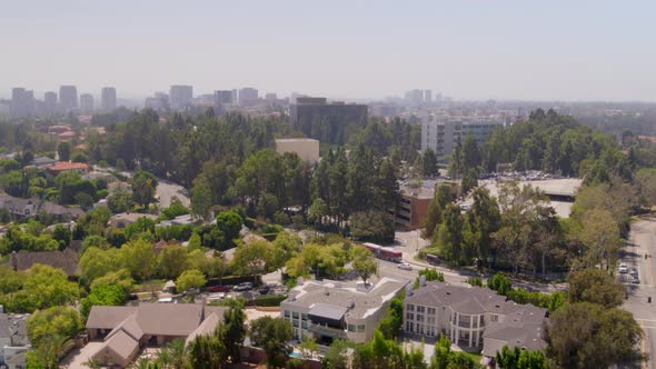 Aerial of houses and vehicles riding on road in city on a sunny day alt