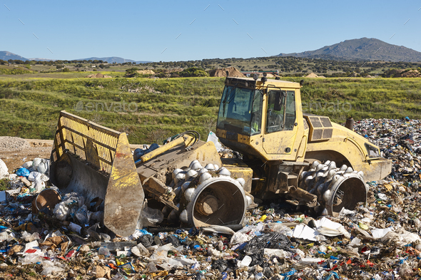 Heavy machinery shredding garbage in an open air landfill. Pollution - Stock Photo - Images