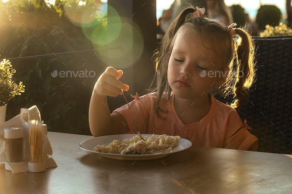 children have lunch in an outdoor cafe on the street Stock Photo by olgar23