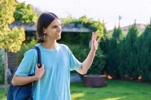 Portrait of teenage guy in profile, waving hand outdoor