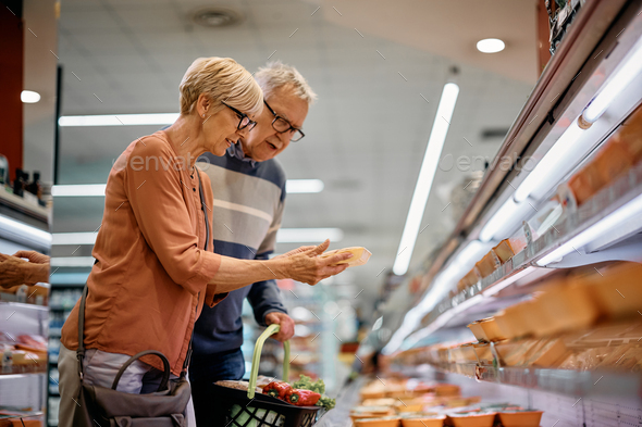 Mature couple buying products at supermarket\'s refrigerated section.