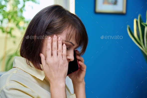 Sad middle aged woman talking on the phone