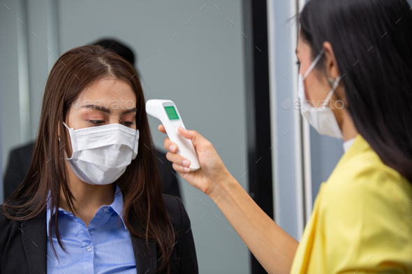 Asian woman scanning infrared thermometer checking fever to colleagues ...