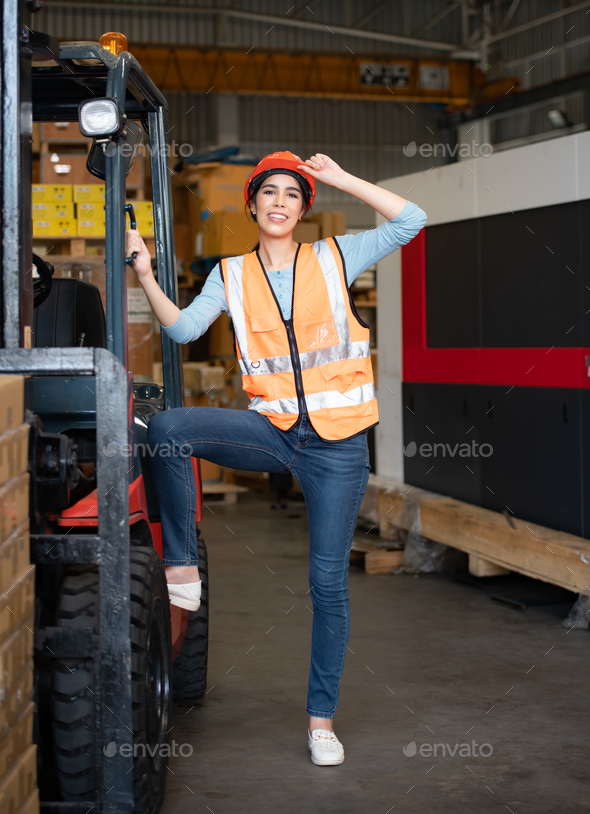 Portrait of an Asian woman with a forklift used to lift heavy objects in a warehouse.