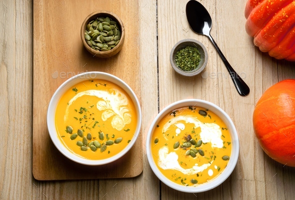Yellow Pumpkin Soup with cream, pumpkin seed, and parsley on wooden background. Copy space. Top view - Stock Photo - Images