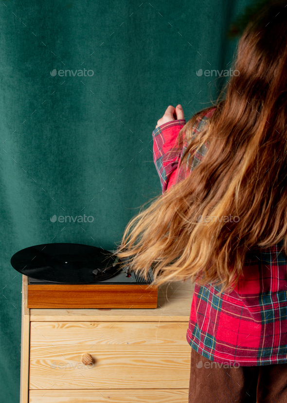 Teen girl listen a record and dancing next to record player