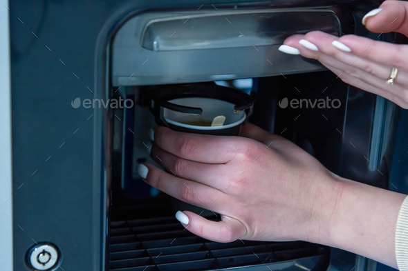 Woman picking up coffee cup from vending machine