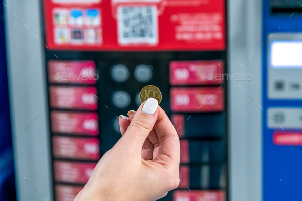 Woman holds 10 rouble coin by vending machine