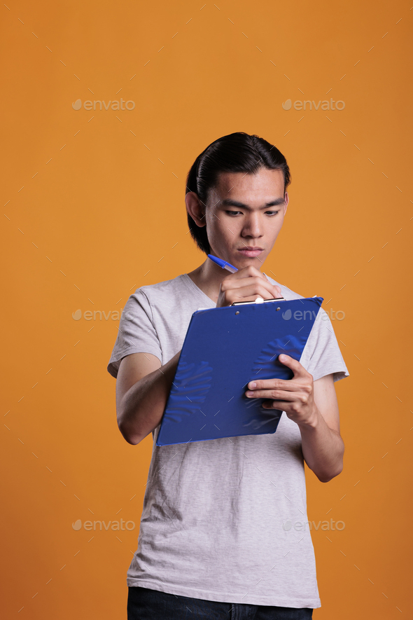 Young asian man filling survey form in clipboard