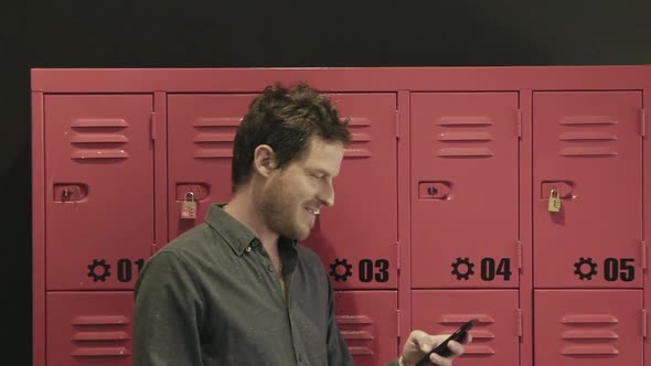 Man standing in front of lockers using smart phone
