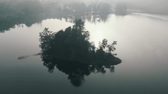 Aerial view of a misty lake and a small island in the middle with fog in the morning