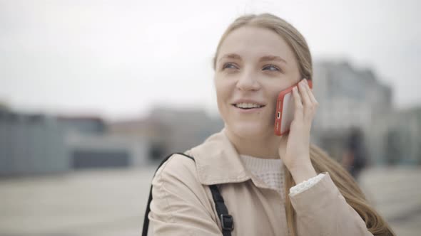 Camera Moves Around Beautiful Face of Young Charming Caucasian Woman Talking on Smartphone. Close-up alt