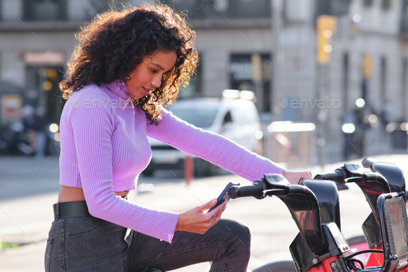 Woman using mobile phone app to rent a bike. - Stock Photo - Images