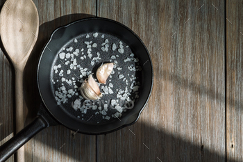 Cast Iron Frying Pan with Salt and Garlic on a Rustic Loft Wooden Table. Kitchen Food Background