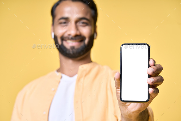 Happy indian man showing mobile phone mockup screen isolated on yellow ...