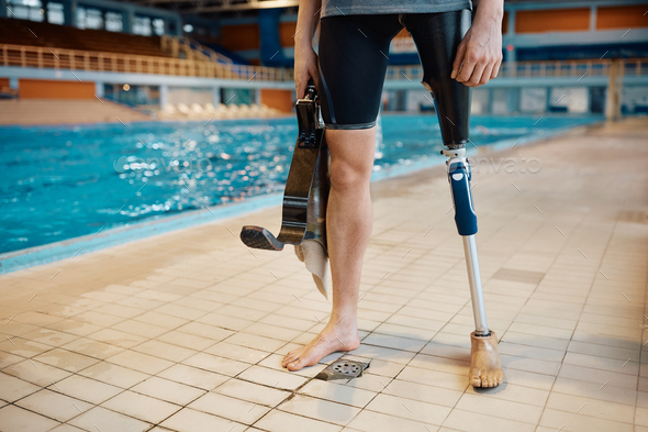 Unrecognizable amputee athlete at pool side of indoor swimming pool ...