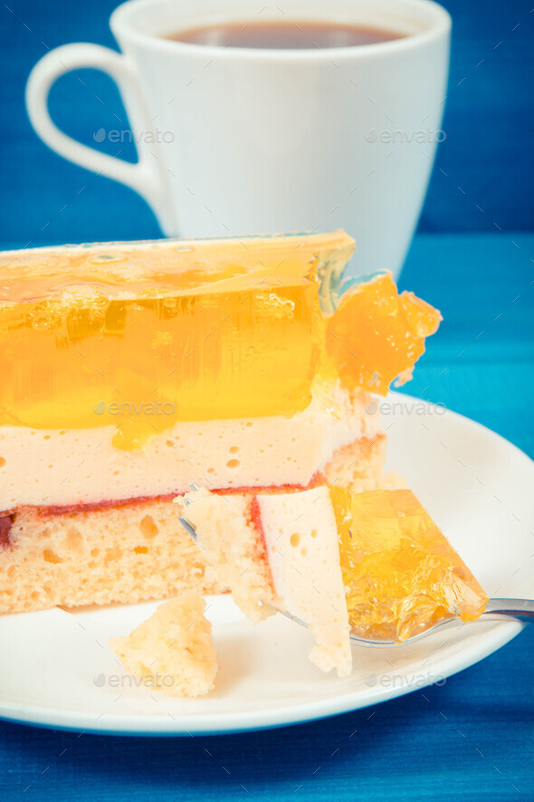 Creamy sweet sponge cake with different layers and jelly. Cup of coffee. Festive dessert