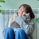 Middle-aged woman in sweater with cat sitting near heating radiator - PhotoDune Item for Sale