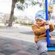 A boy on a playground in an autumn park rides on a swing in cloudy weather - PhotoDune Item for Sale