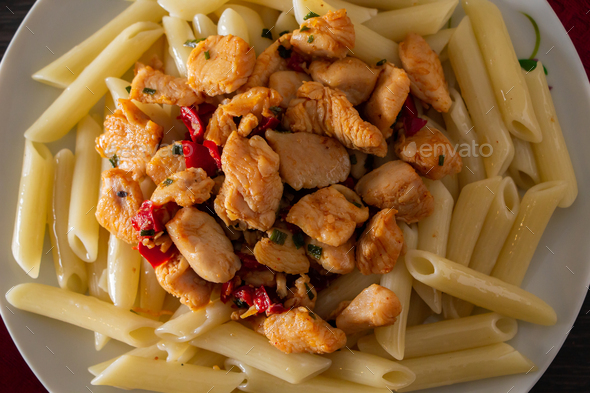 Penne pasta with chicken and vegetables in tomato sauce Stock Photo by