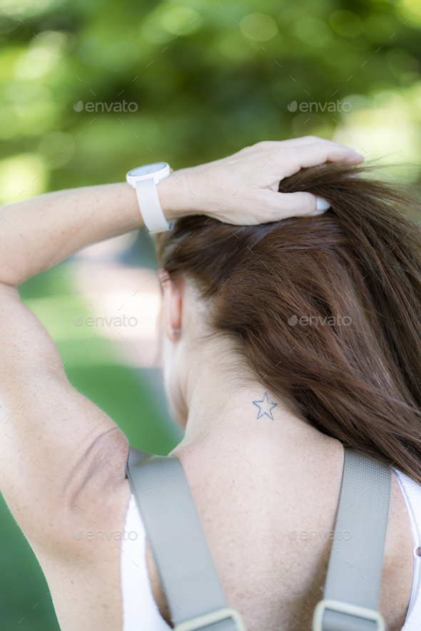woman has her hair tied up and a star tattoo is visible on her neck