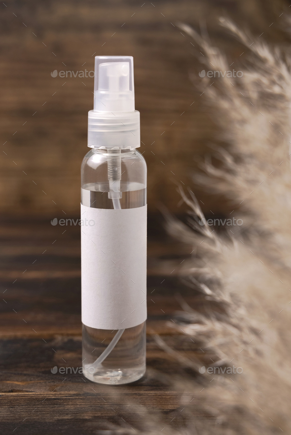 Cosmetic spray bottle on wood near pampas grass close up. Label Mockup