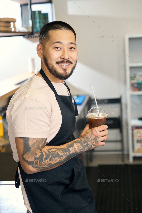 Goodlooking guy working as barista and holding a drink Stock Photo by