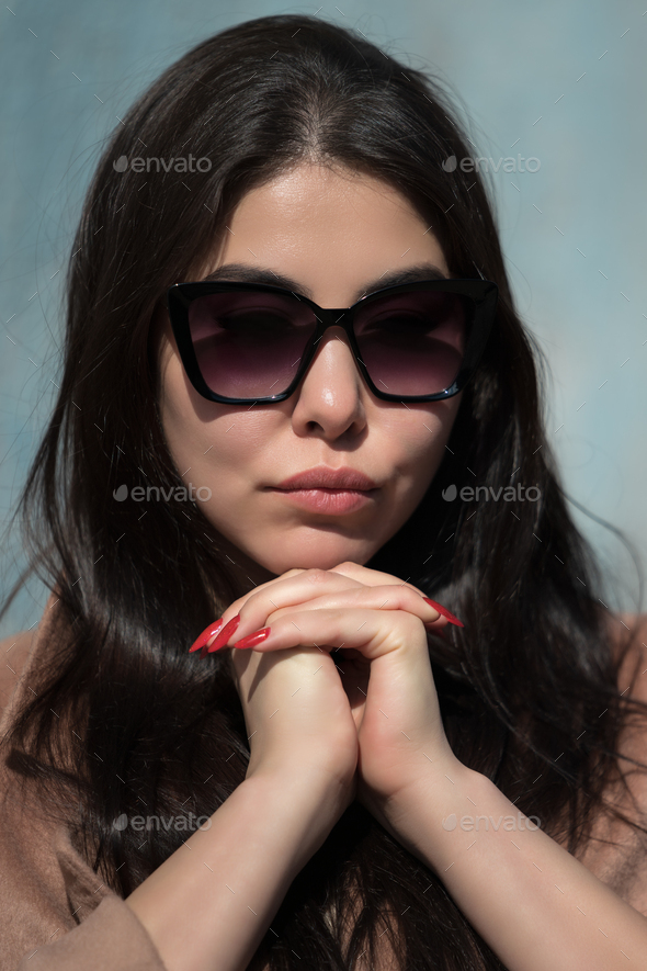 Glamorous young woman with plump lips and glasses folded hands under ...