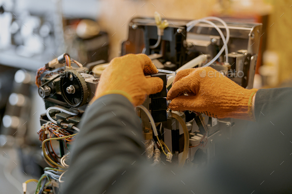 Male electrician hands repairing coffee machine in workshop