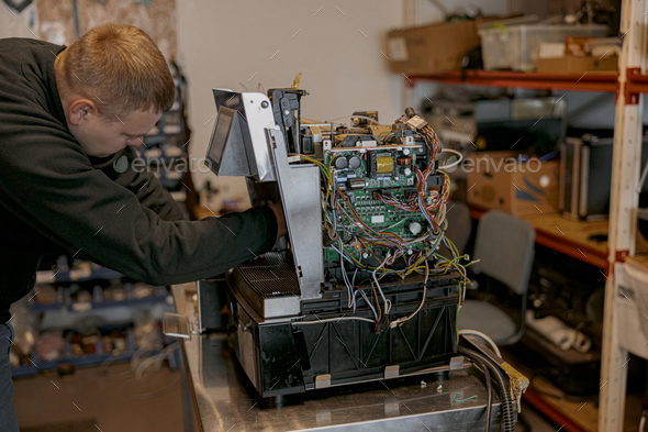 Male electrician repairing coffee machine in workshop