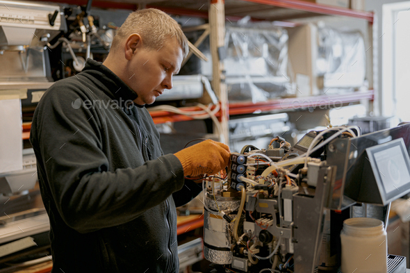 Male electrician repairing coffee machine in workshop