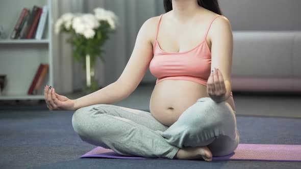 Pregnant Woman Practicing Yoga at Home, Calming Herself and Her Future Baby alt