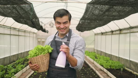  Male farmer sprays water from foggy with happy smile in plantation greenhouse.
