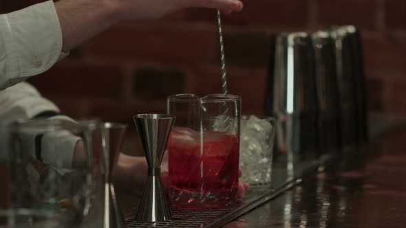 Professional Bartender at Work in Bar Mixing Ice and Liquor in Glass for Drink alt