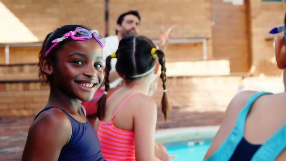 Smiling girl sitting near poolside alt