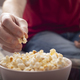 Caucasian man sitting on sofa with popcorn and tv remote - PhotoDune Item for Sale
