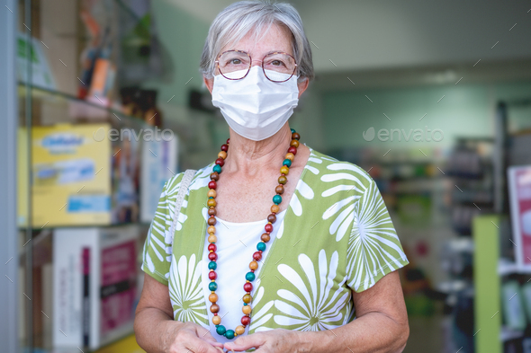 Senior woman wearing mask entering in pharmacy to buy medical products