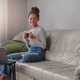 Young beautiful mixed-race female sitting on couch and smiling to camera holding cup of - PhotoDune Item for Sale