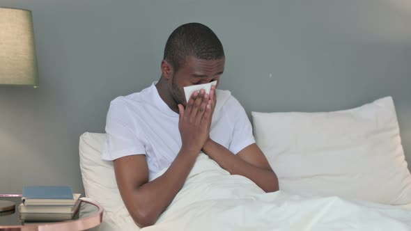 Allergic Young African Man Sneezing in Bed  alt