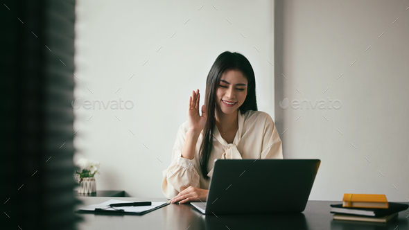 Smiling woman waving hand, chatting online, video call conference with her remote team on computer.