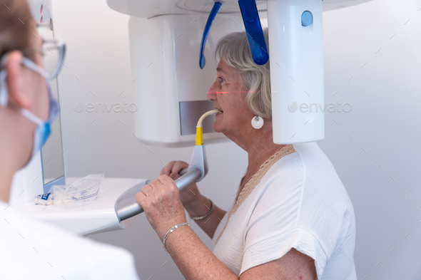 Dental clinic, dental assistant with an elderly woman in the x-ray room, explaining how they have