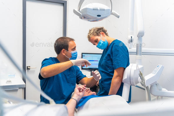 Dental clinic, dentist doctor and assistant examining the teeth of an elderly woman lying the table