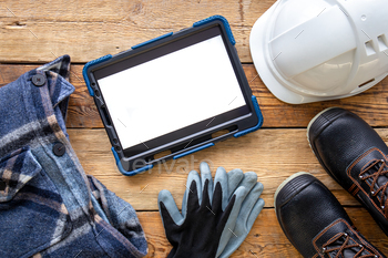 Builder uniform and digital tablet on wooden background, flat lay.