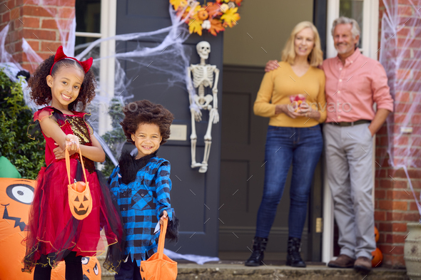 Portrait Of Grandchildren Dressing Up To Visit Grandparent\'s House Trick Or Treating On Halloween