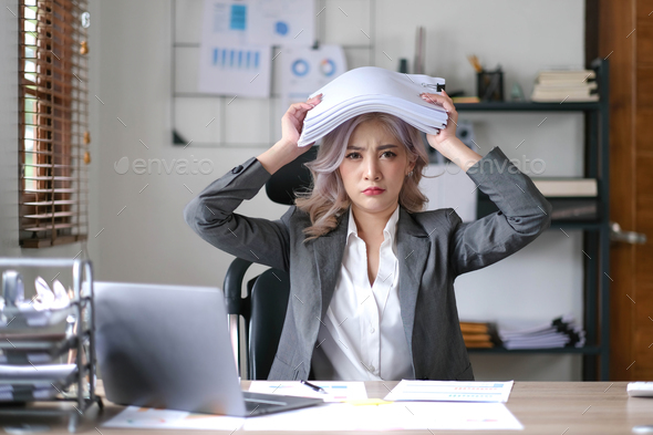 Portrait of beautiful asian woman at the desk with paperwork on her head.