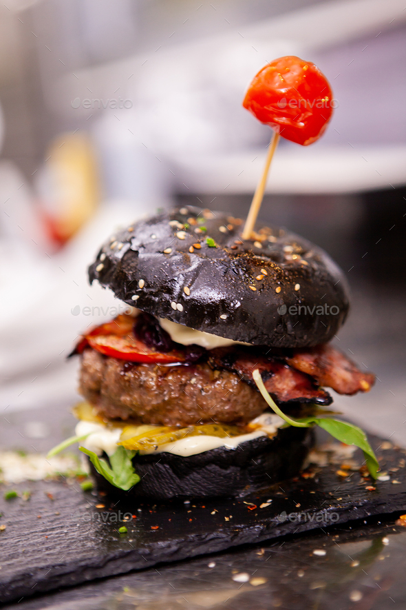 Black burger on stone cutting board Stock Photo by DC_Studio