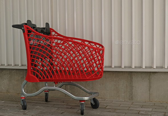 Empty red shopping on industrial wall background. Shop trolley at supermarket. Sale, discount, shopa