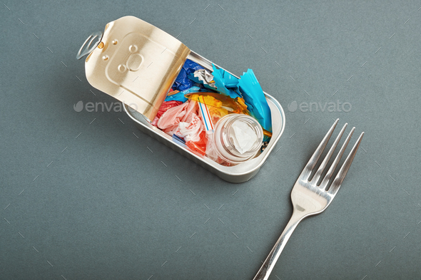 Open tin can and fork. Plastic waste instead of fish inside. Ocean plastic pollution concept