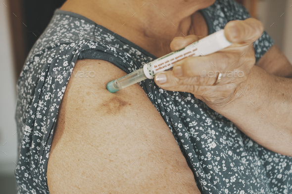 Close up of woman arm with insulin pen. Mature lady injecting diabetes treatment with syringe
