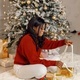 Black girl near Christmas tree opening gift at home - PhotoDune Item for Sale